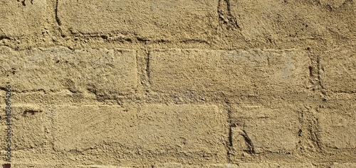 Close-up of a rough beige brick wall with textured surface. Rustic and aged background ideal for construction, architecture, and design projects