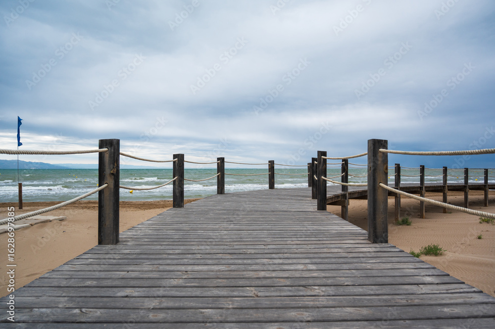 Fototapeta premium Wooden boardwalk leading to the sea on a cloudy day