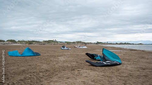 Kitesurfing equipment lying on sandy beach on cloudy day