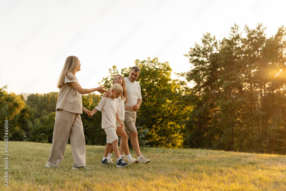 Fototapeta premium Happy family walking in nature during sunset, enjoying time and bonding outdoors