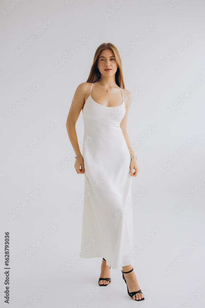 Naklejka premium Fashion model posing in white dress and black high heels