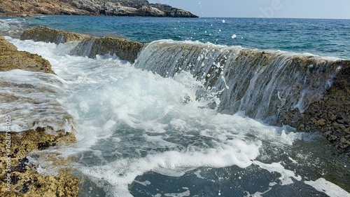Small waves gently splash through natural stone slabs on Kory Beach in Alanya, Turkey. Peaceful seaside view perfect for travel, relaxation, and nature themes