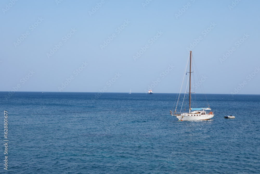 Obraz premium Serene Ocean View with a Sailboat Under a Clear Blue Sky
