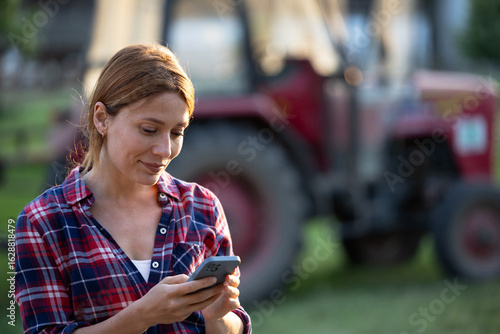 Obraz na plátně Female farmer using phone outdoors early in morning