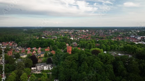 Aerial orbit of water tower in spa park of Mölln the Eulenspiegel town and residential areas. Red brick water tower nestled within the spa park of Mölln.