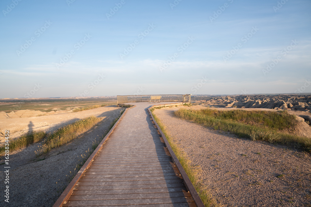 Fototapeta premium Wooden boardwalk trail at sunrise in Badlands National Park, South Dakota