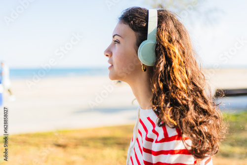 Young woman wearing headphones listening to music by the sea