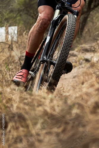 A close-up of a mountain bike in action on rough terrain. The gears and suspension are captured with great clarity, conveying strength, endurance, and adrenaline.