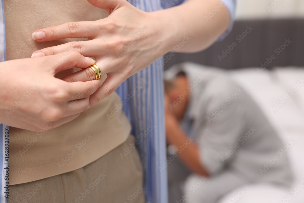 Fototapeta premium Woman taking off engagement ring after her husband's betrayal indoors, selective focus