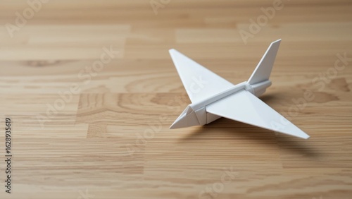 Origami Paper Plane on Wooden Desk. Business and Travel Concept. Minimalist White Airplane