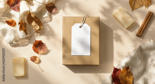 Gift box with blank tag, autumn leaves and soap on beige background