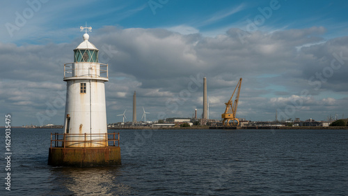 Wallpaper Mural White lighthouse standing tall in the sea with industrial cranes in the background under a cloudy sky Torontodigital.ca