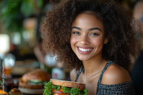 Woman smiling with a hamburger in hand.