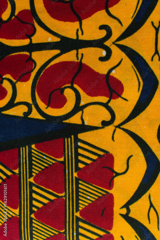 Obraz premium top view of red yellow ankara fabric, flatlay of nigerian wax cloth with designs, spread out red yellow ankara material