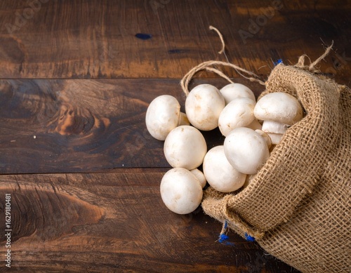 Fresh Mushrooms in Burlap Sack on Wooden Table
