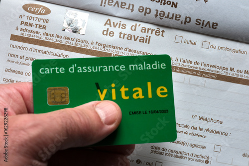 French health insurance card Vitale held above a sick leave certificate form, representing healthcare, insurance, and social security in France.