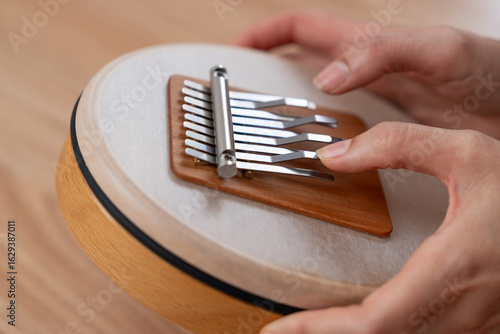 Hands of a woman playing the Hokema Sansula musical instrument.