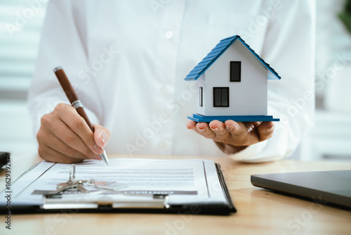 Real estate agents present home designs and discuss documents that reflect real estate investing, property purchases, mortgage planning, home loans, financial advice, and safe housing decisions.