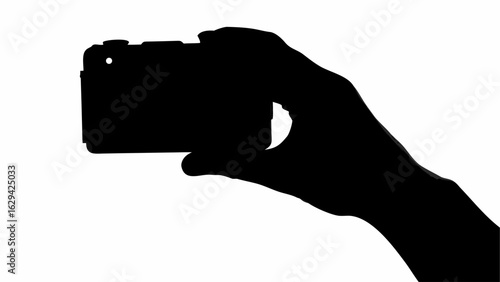 Silhouette of a hand holding a compact camera with the index finger extended for taking a picture