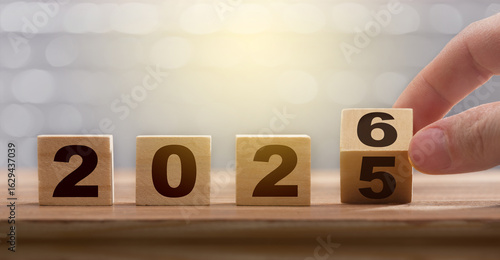 The transition from 2025 to 2026 on a wooden calendar. A conceptual image representing the new year, the passage of time, and new beginnings, featuring soft lighting and a blurred background.