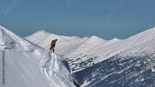 Skier evaluating snowy ridge line in mountain landscape