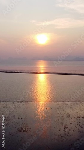 Wallpaper Mural Vertical video Sunset Serenity: The sun gracefully dips towards the horizon, casting a warm golden glow over the tranquil ocean, mirroring its light onto the wet sand below Torontodigital.ca