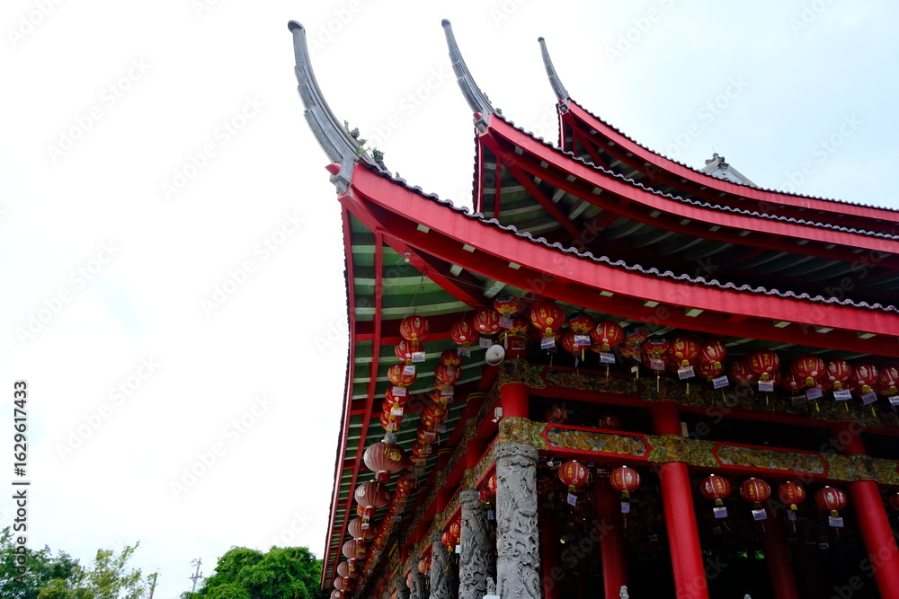 Fototapeta premium Red-roofed Sam Poo Kong temple in Semarang, Indonesia, with traditional Chinese architecture, red lanterns, and guardian lion statues.