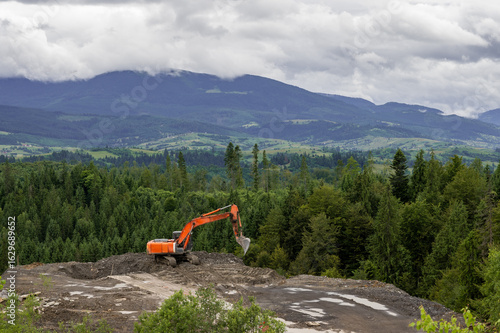 orange excavator works in the mountains