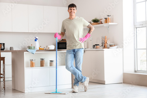 Young man with mop in kitchen
