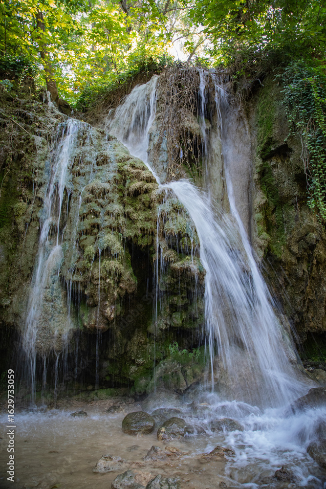 Fototapeta premium Peaceful waterfall in a Croatian national park surrounded by lush greenery and clear water. A stunning natural landscape ideal for travel, nature, adventure, and outdoor-themed content