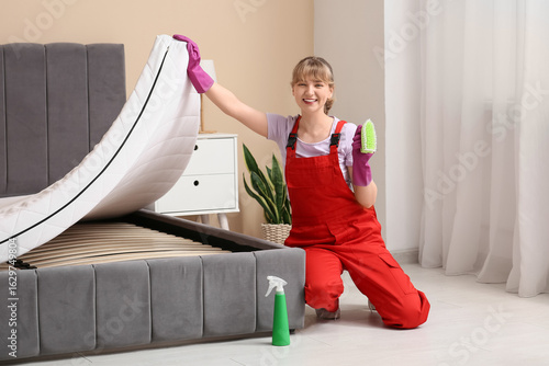 Female janitor cleaning mat...