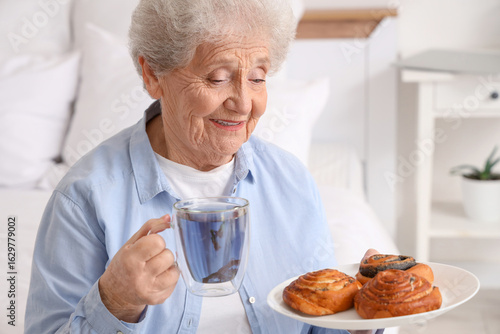 Senior woman with glass cup...