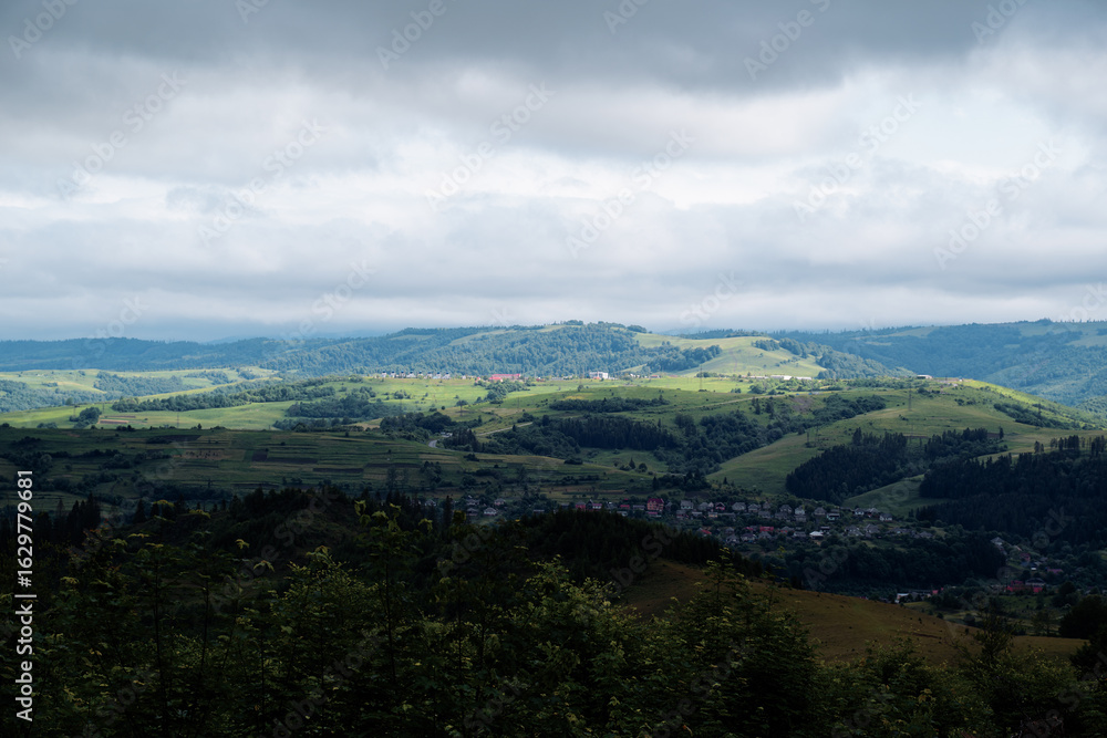 Fototapeta premium Scenic Countryside Landscape with Rolling Hills and Overcast Sky
