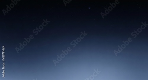 A serene view of the deep night sky with a few faint stars, showing a dark blue gradient to a light haze on the horizon.