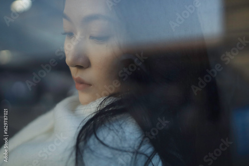 Pensive young Asian woman with long hair.