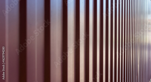 A modern corrugated metal panel fence with a vertical, repetitive pattern.