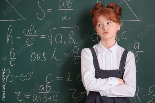 Fotografie Thoughtful schoolgirl near chalkboard. Children's Inventor's Day
