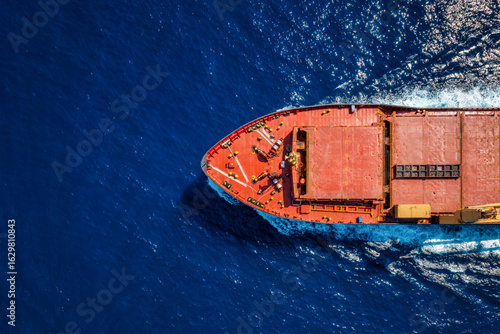 Aerial overhead view of a general cargo or container ship traveling with speed over the ocean with copy space