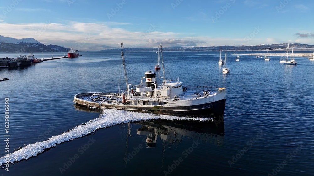 Fototapeta premium Saint Christopher Boat In Ushuaia Tierra Del Fuego Argentina. Aerial View Of A Bustling Downtown Cityscape With Modern Buildings. Nature Tourism Icon Snow Covered Forest Trees.