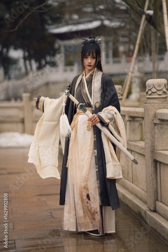 Fotografía Elegant young woman in traditional attire holding a sword.