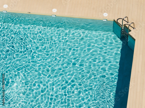 Vista desde arriba de una piscina y la escalera de acceso a pleno sol en verano	