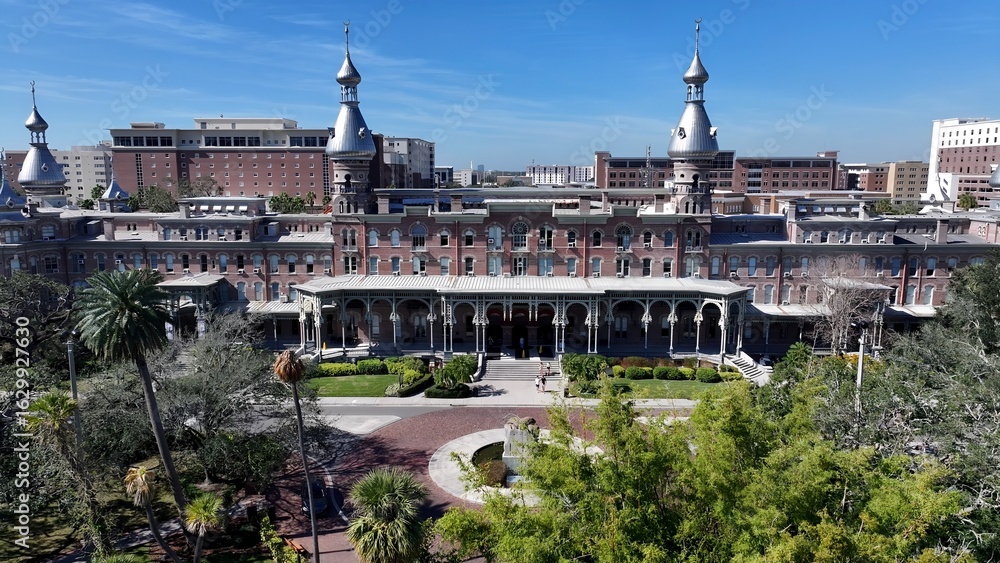 Fototapeta premium Henry Plant Museum In Tampa Florida United States. Drone Captures A Garden With Sidewalks Surrounded By Lush Trees. Town Clouds Sky Backgrounds Urban. Backgrounds Downtown Panoramic City.