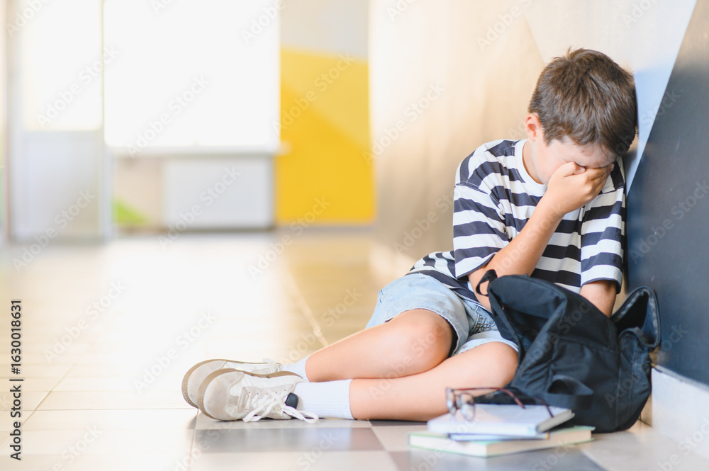 Schoolboy crying in school hallway after bullying incident Schoolboy crying in school hallway after bullying incident