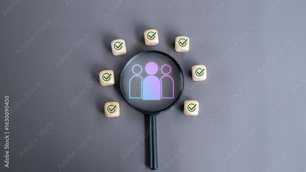 Fototapeta premium Magnifying glass highlighting a group of people icon surrounded by checkmark blocks on a gray background. Concept of HR recruitment, team selection, and talent matching.