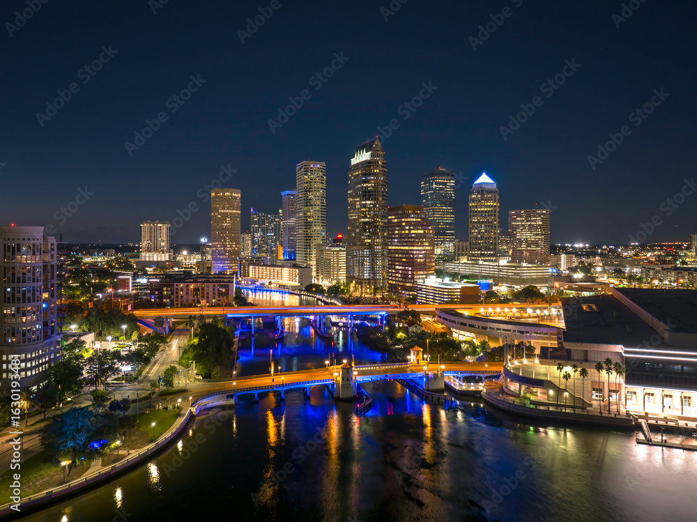 Obraz premium American city skyline of Tampa in Florida. Brightly illuminated commercial buildings and highway bridge over Hillsborough river. Night urban landscape of downtown district in USA.