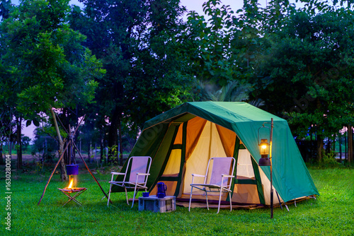 Camping tents at night, vintage cabin tents, antique oil lamps, retro chairs, and a group of camping tents with outdoor coffee-making facilities on tables in a forest camping area.