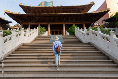 Obraz na plátne young woman tourist climbing the stairs in Jing'An Temple- shanghai, China