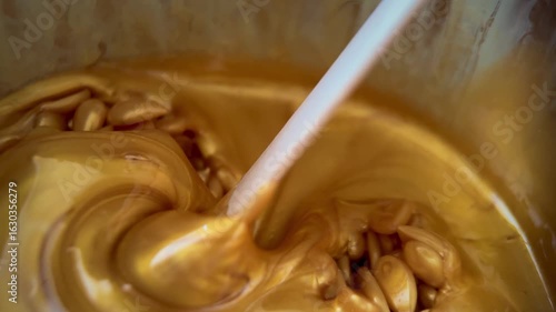 Liquid yellow, gold depilatory wax or sugar paste on a wooden stick close-up. Master mixes the heating wax with a wooden spatula before the depilation waxing procedure. 
