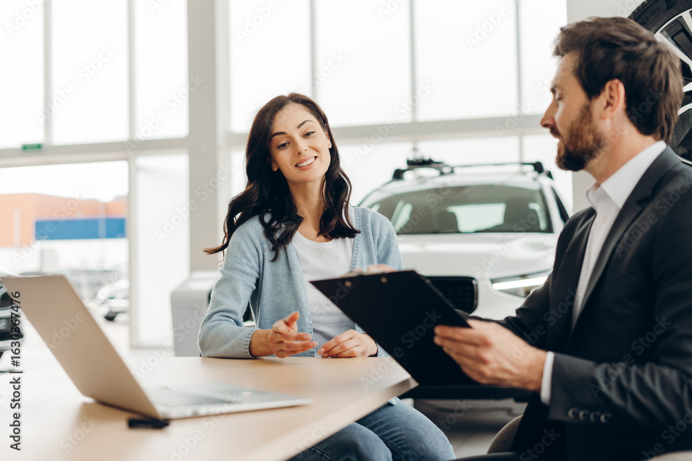 Car salesman showing contract to customer in dealership Car salesman showing contract to customer in dealership