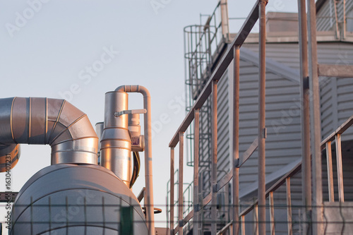 pipeline elements near industrial building against blue sky close-up